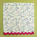A confetti print fabric napkin from Madcap Cottage on a light green background.