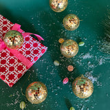 six mini gold disco ball ornaments on a green background