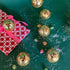 six mini gold disco ball ornaments on a green background