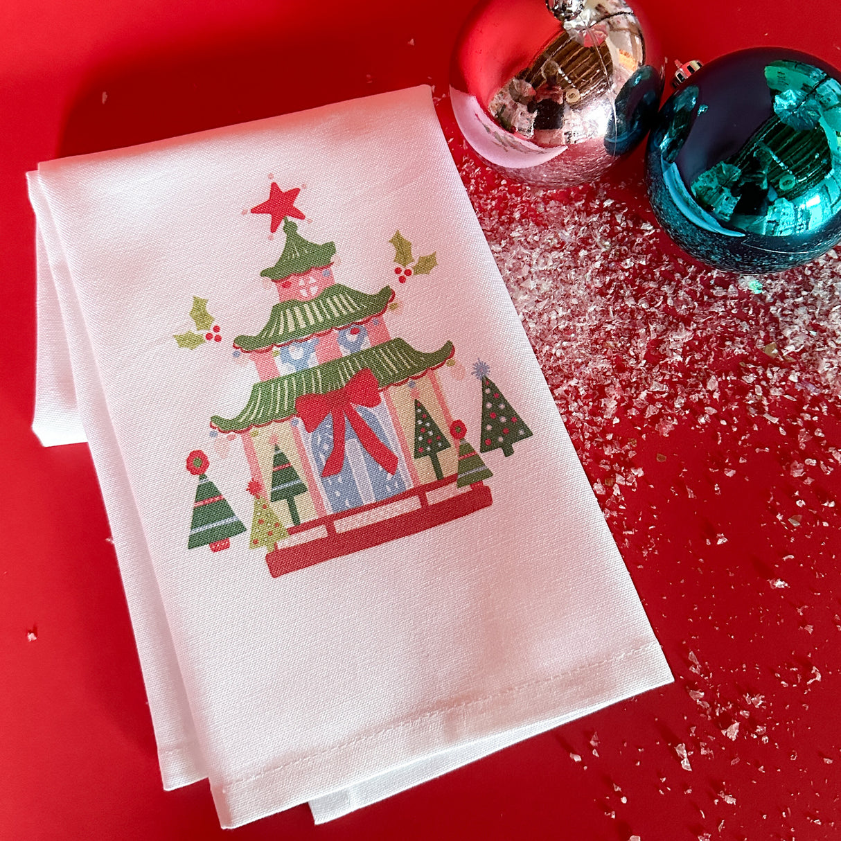 White Christmas tea towel with a colorful pagoda motif surrounded by christmas trees
