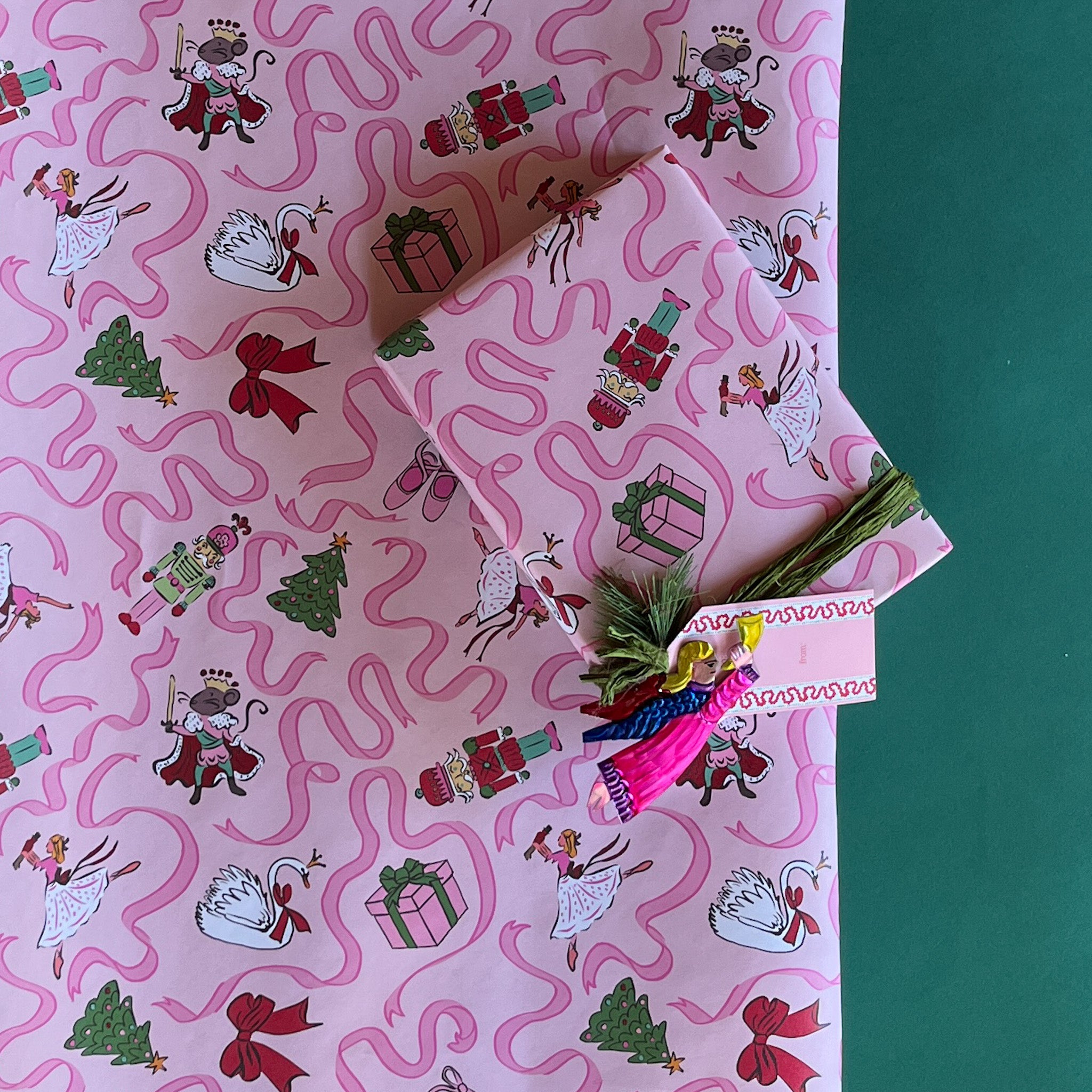 Pink Christmas wrapping paper featuring nutcracker and ribbon motifs.