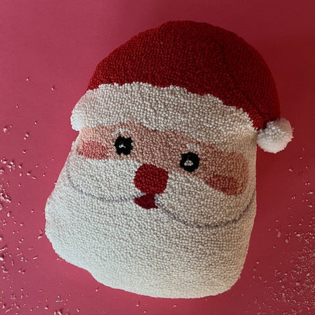 A hooked wool santa pillow in the shape of a friendly santa face