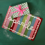 A striped rectantgular Christmas rug that says "sparkle" and has a white scalloped motif at the border