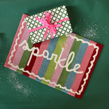 A striped rectantgular Christmas rug that says "sparkle" and has a white scalloped motif at the border