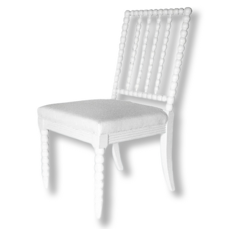 A white dining chair with bobbin detailing on back and legs. 