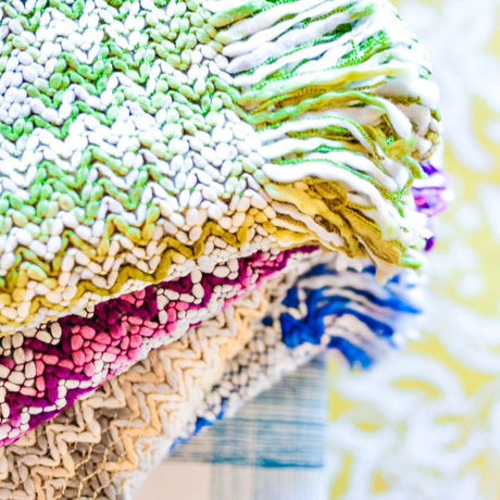 a pile of colorful throw blankets featuring a woven zig zag design