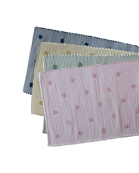 four cotton washable accent rugs from madcap cottage in navy blue, yellow, green and pink featuring a repeating daisy motif.