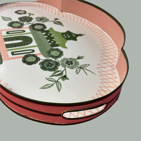 A pink and green metal tray featuring a central pagoda motif surrounded by blossoms. 