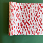 A white and red paper table runner featuring a brushtroke pattern called Club House by Madcap Cottage
