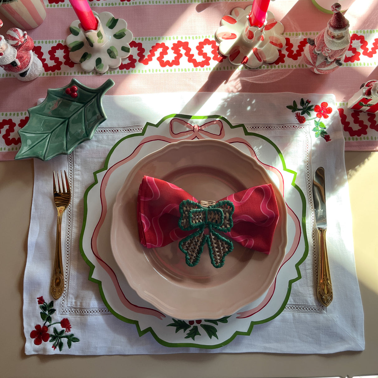 A tablesetting comprised of an embroidered floral linen placemat and handpainted charger with ribbon motif.