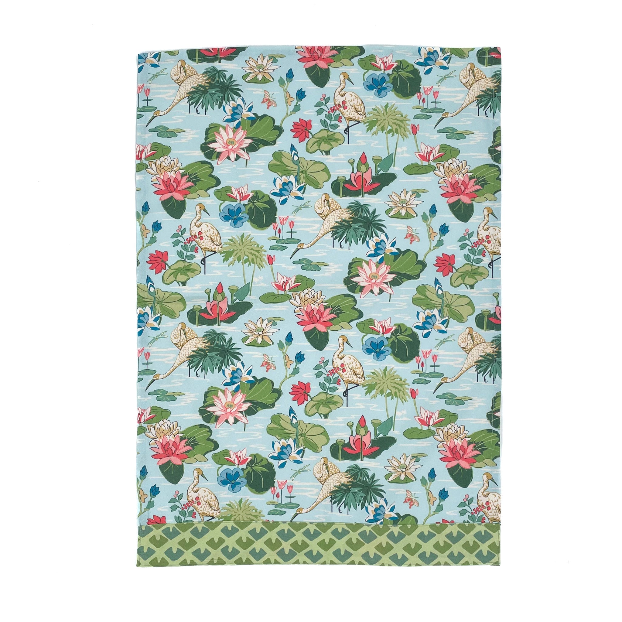 a green and blue floral tea towel with heron and waterlily motifs against a white background. 