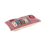 Rectangular pink holiday pillow with hooked texture and “Merry & Bright” text in colorful letters.