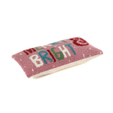 Rectangular pink holiday pillow with hooked texture and “Merry & Bright” text in colorful letters.