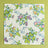 A multicolor bunny and strawberry print fabric Easter napkin against a green background. 