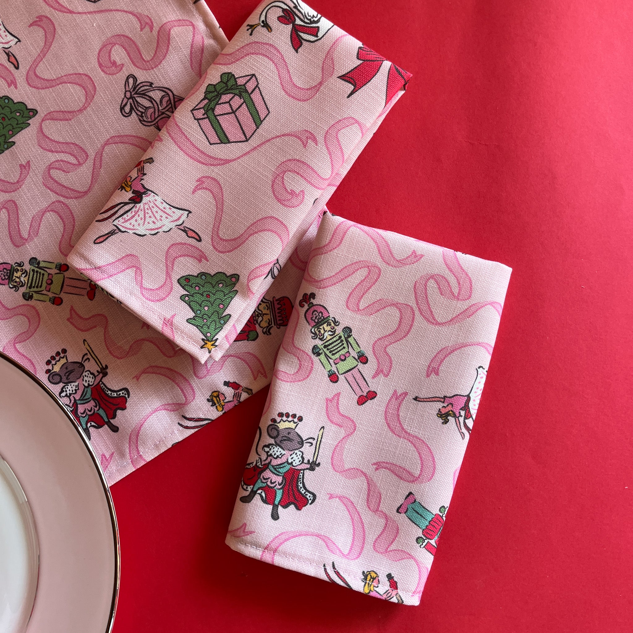 Nutcracker Ribbons Christmas Cloth Dinner Napkins folded on a red background