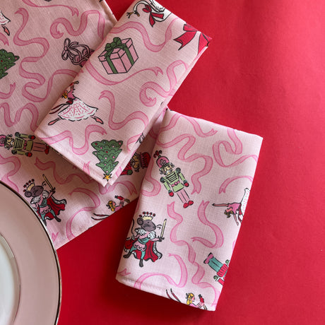 Nutcracker Ribbons Christmas Cloth Dinner Napkins folded on a red background
