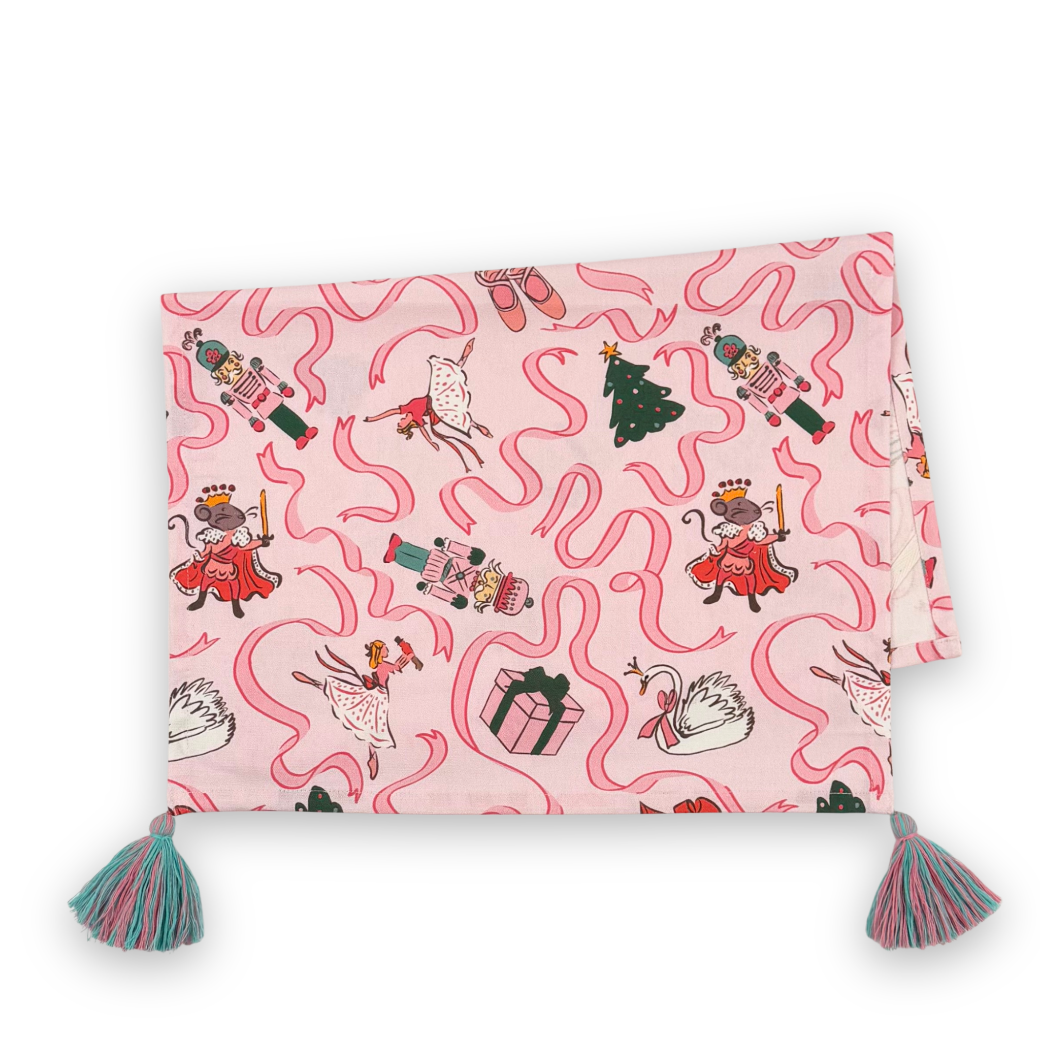 a folded pink christmas tea towel with nutcracker ballet motifs of swans, ribbons, christmas trees, ballerinas and nutcrackers against a white background. 