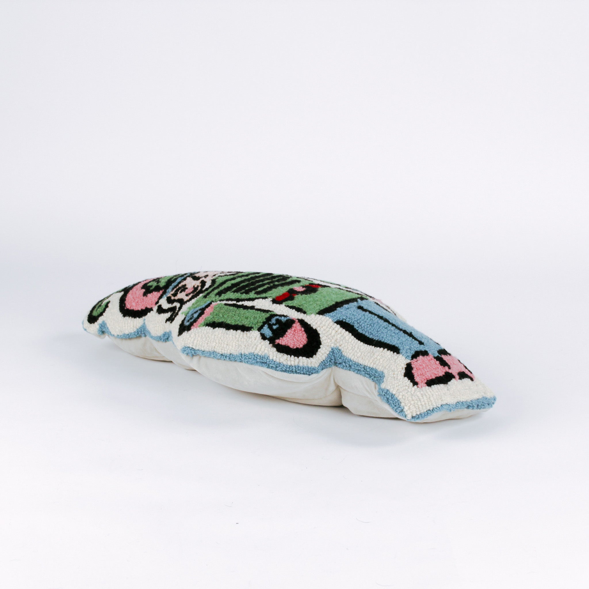 Decorative Christmas pillow shaped like a nutcracker soldier, featuring a pastel green uniform, pink and blue accents, and a detailed mustached face with a tall plumed hat lying in a white surface