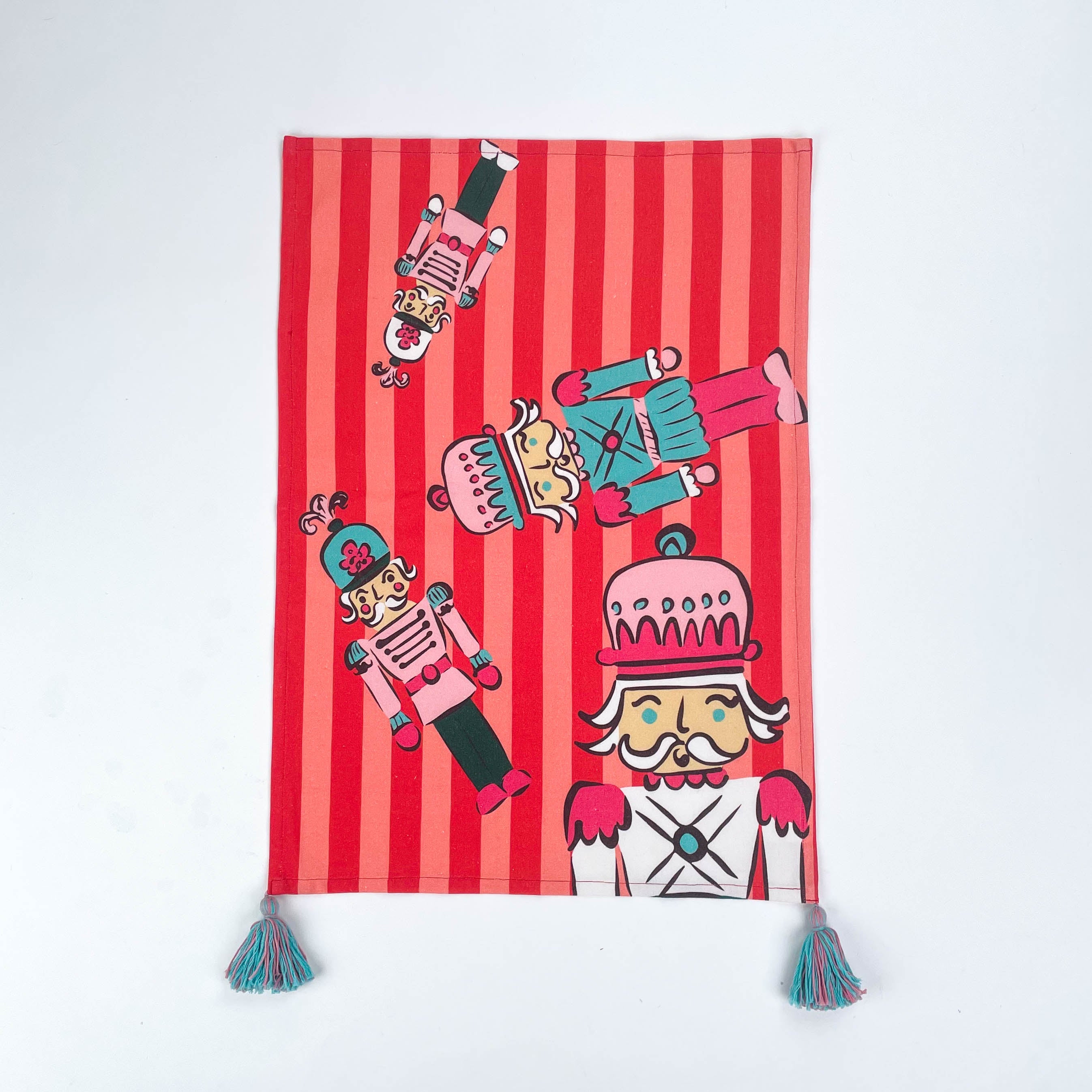 Christmas tea towel featuring colorful nutcracker soldier  with striped background