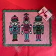 PInk and green christmas rug featuring three nutcrackers and a green scalloped border