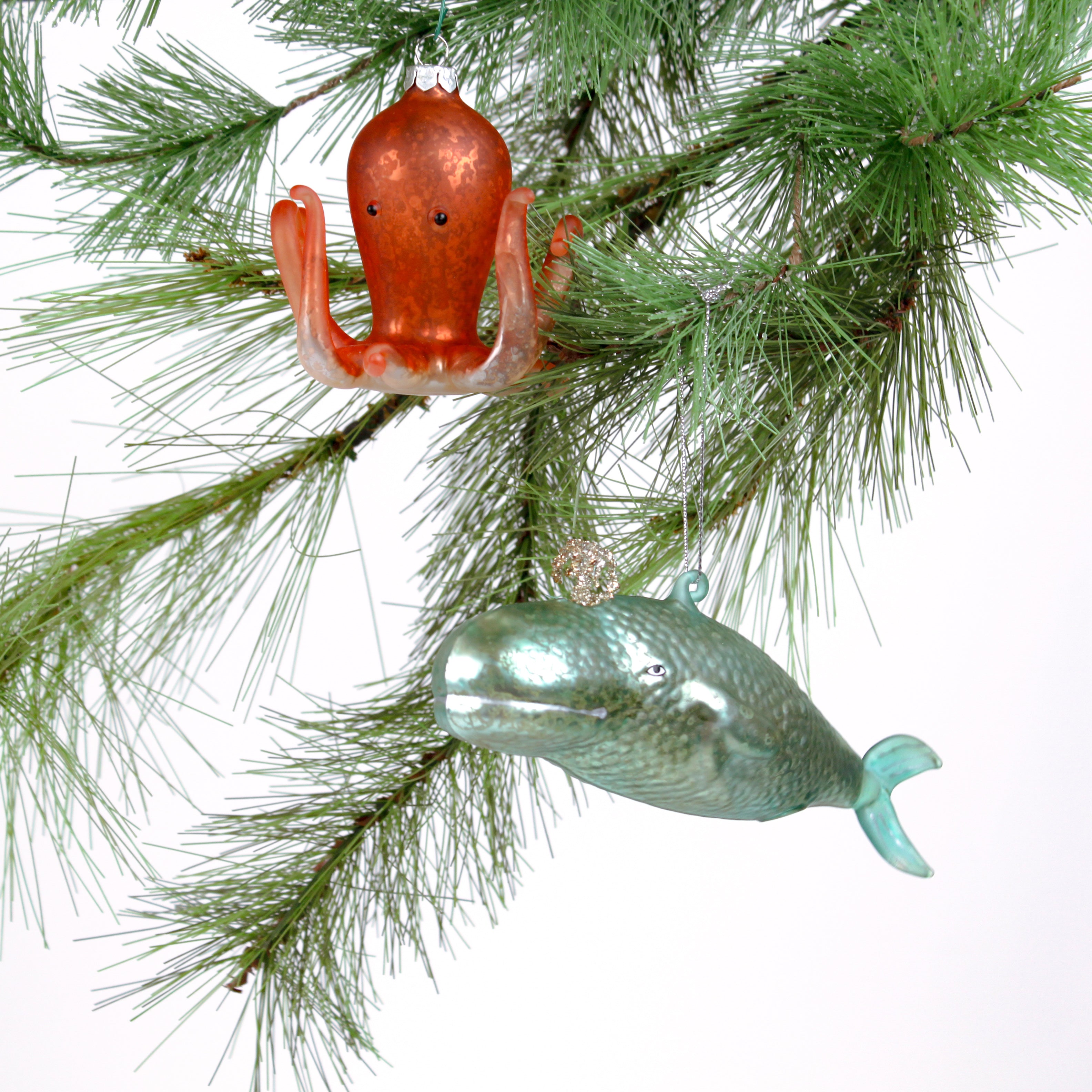 Decorative whale and octopus glass christmas ornaments on a white background