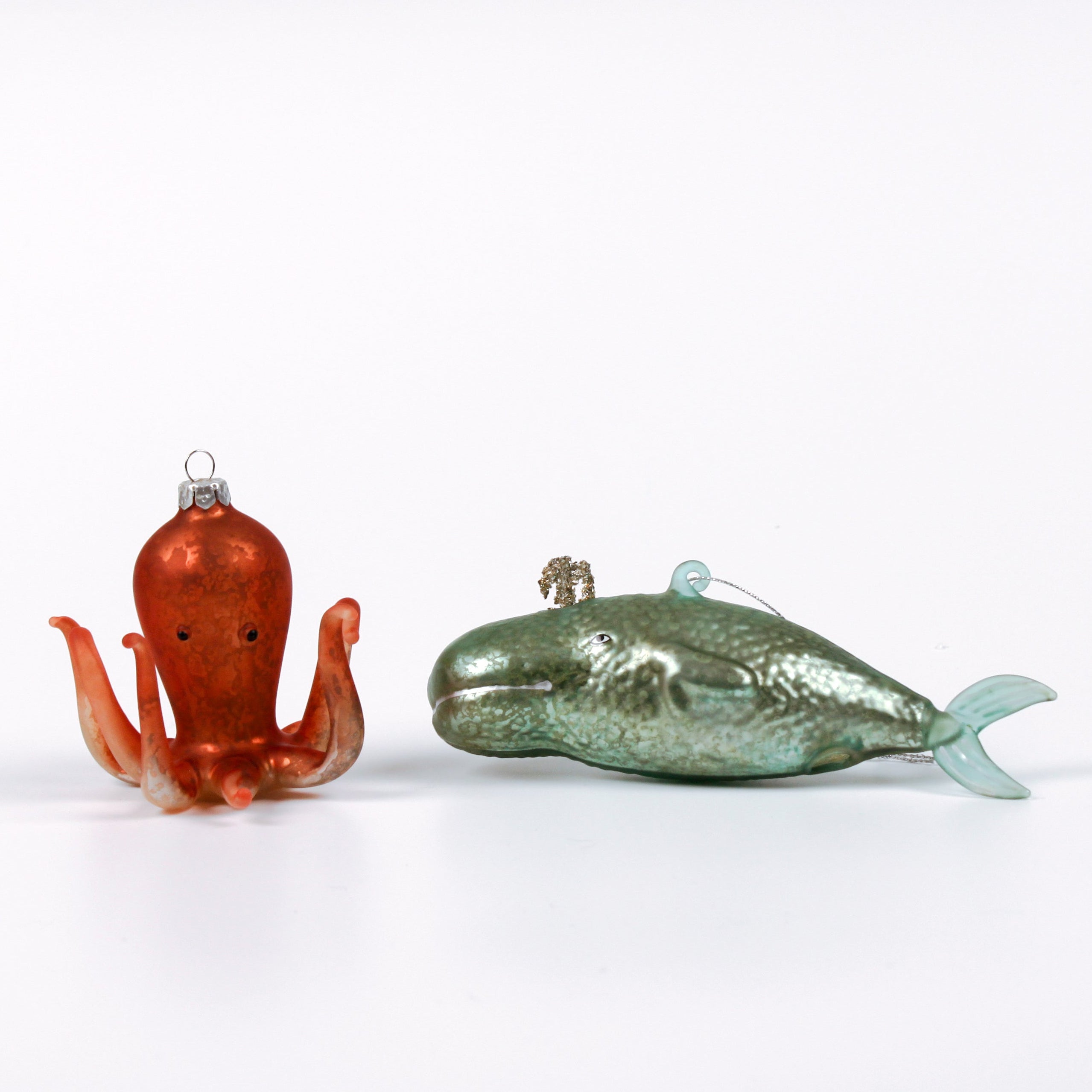 Decorative whale and octopus glass christmas ornaments on a white background