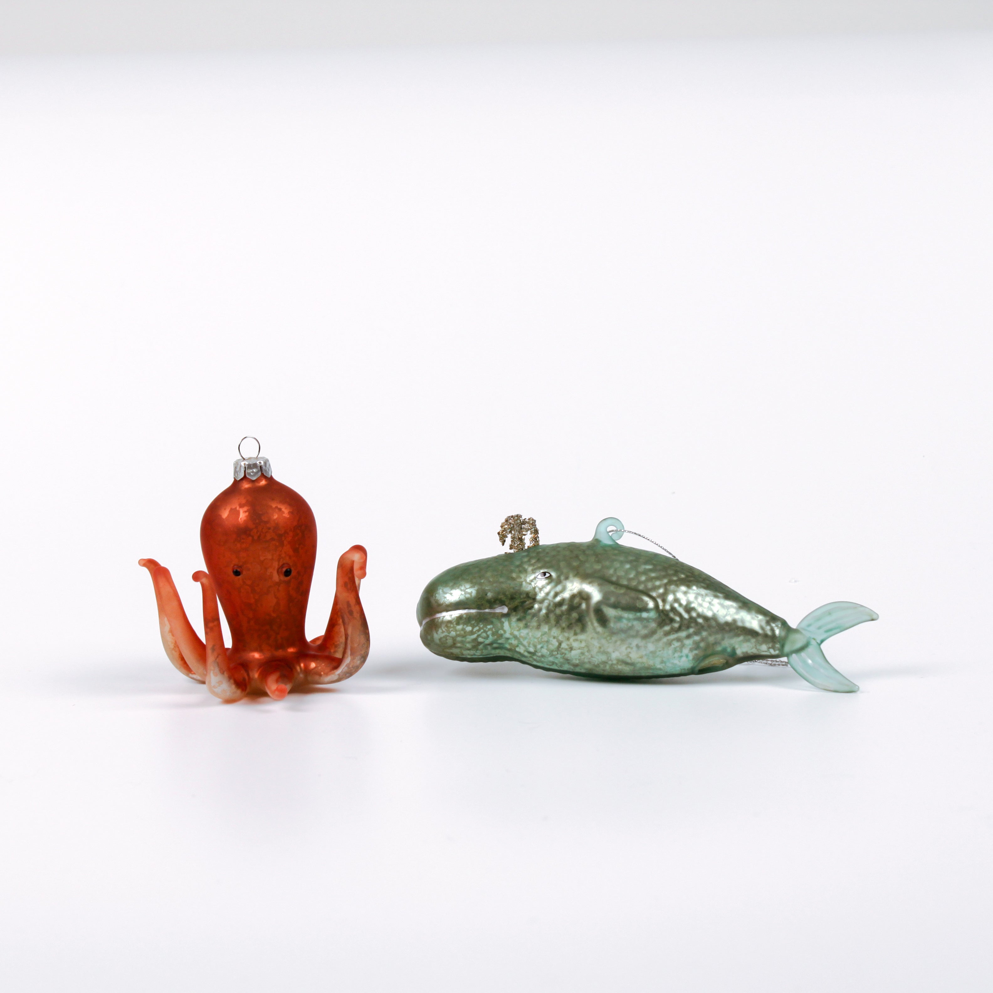 Decorative whale and octopus glass christmas ornaments on a white background
