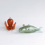 Decorative whale and octopus glass christmas ornaments on a white background