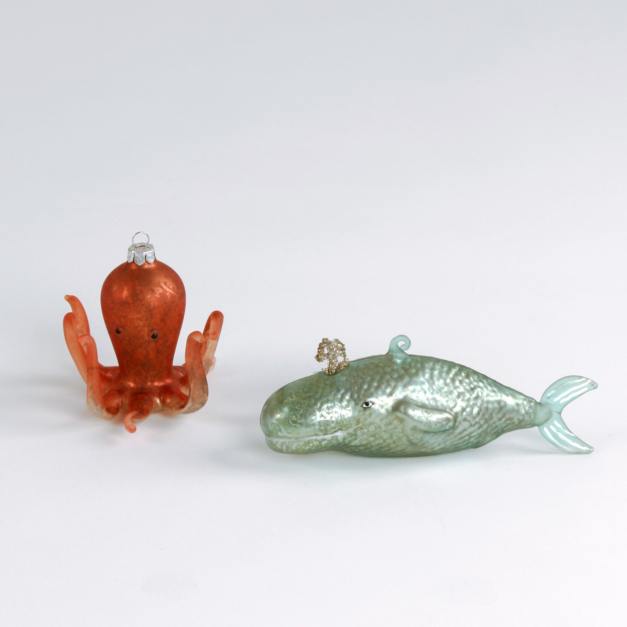 Decorative whale and octopus glass christmas ornaments on a white background