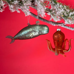 Decorative whale and octopus glass christmas ornaments on a red background