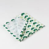 Folded green and light green patterned cloth napkin showing inside seam and fabric texture for table decor.