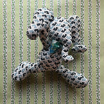 Blue and white patterned stuffed elephant toy with a green bow.