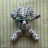 Blue and white patterned stuffed elephant toy with a green bow.