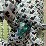 Blue and white patterned stuffed elephant toy with a green bow-cose-up.