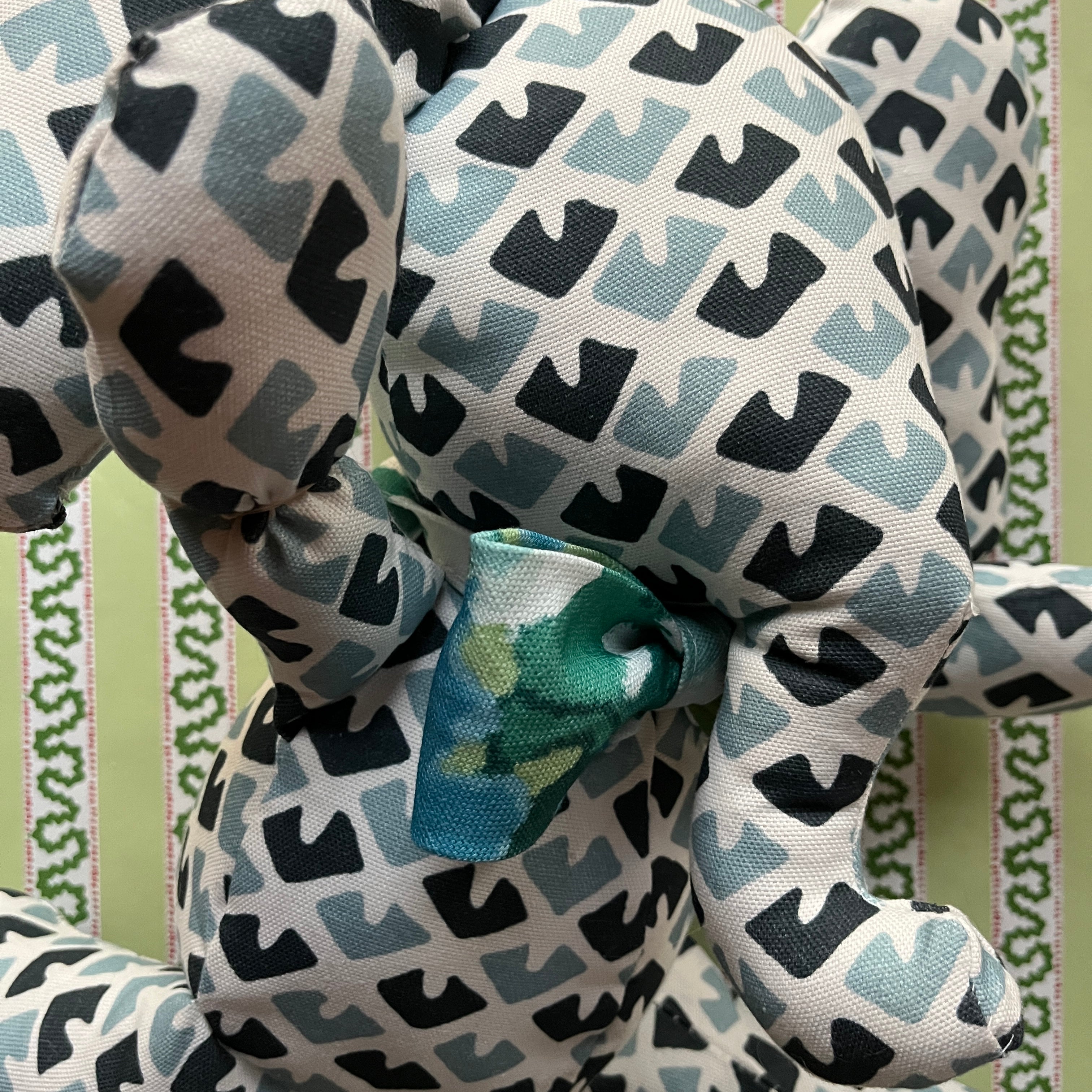 Blue and white patterned stuffed elephant toy with a green bow-cose-up.