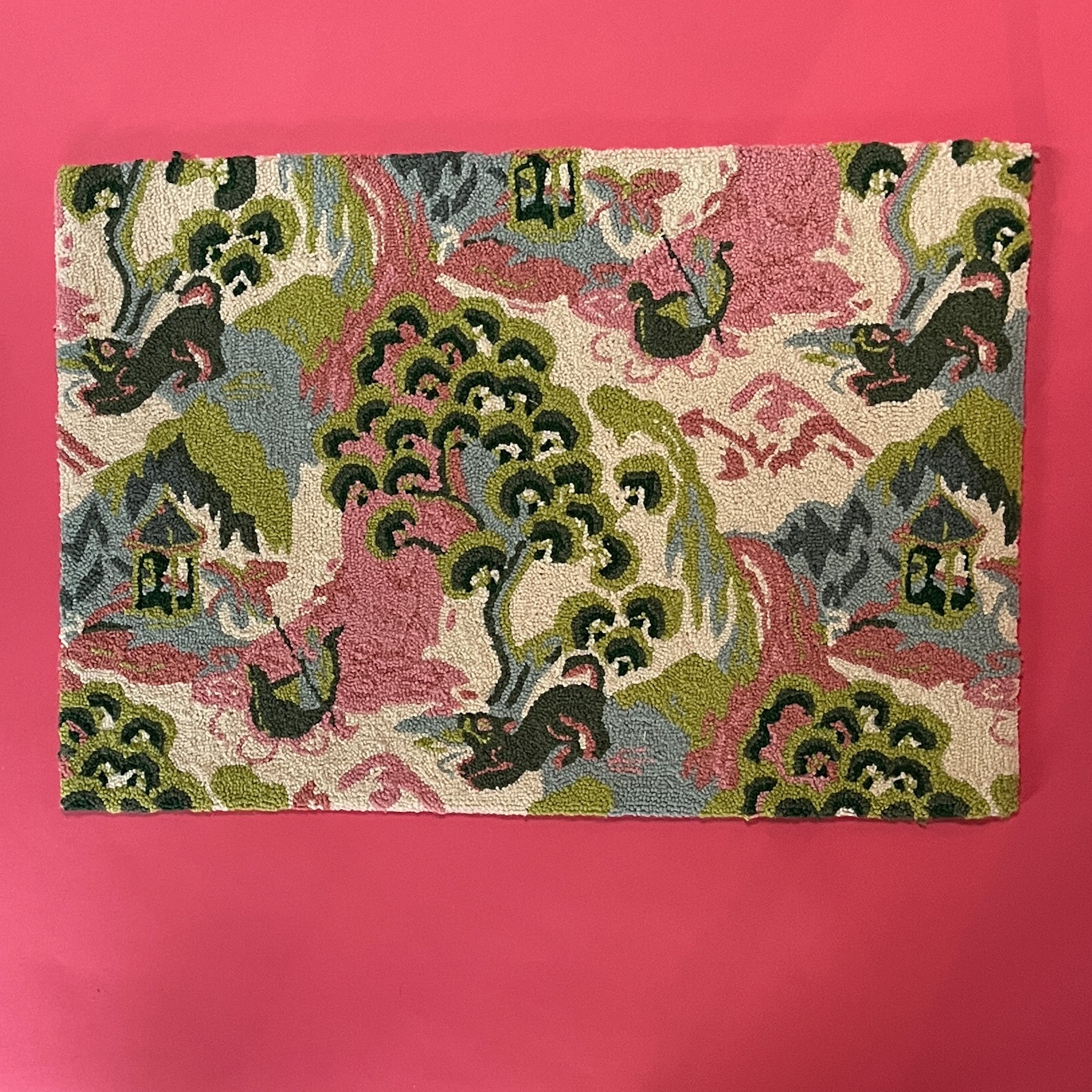 A small pink green and blue rug featuring chinoserie motifs of foo dogs, pagodas and boatmen