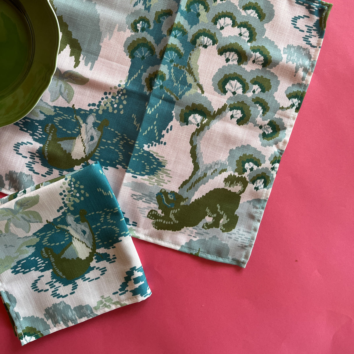 Two Old Peking cloth dinner napkins with a green plate on a red background