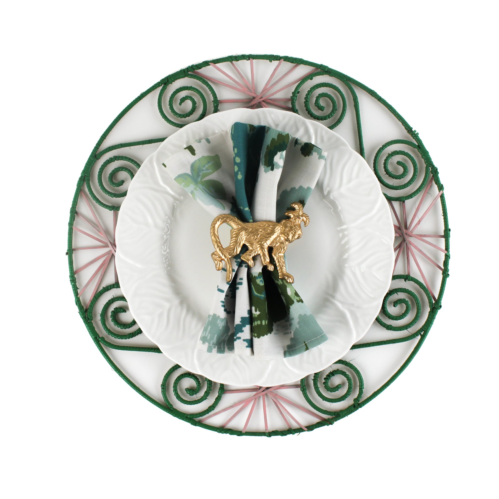 Old Peking chinoiserie dinner napkin in green and blue tones folded and styled on a white plate with a gold monkey napkin ring, displayed on a decorative green placemat for an elegant table setting alongside a Christmas tea towel.