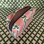 Open view of Harbor Trail toiletry bag in Bahama pink with a green ribbon and blue dash motif.