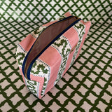 Open view of Harbor Trail toiletry bag in Bahama pink with a green ribbon and blue dash motif.