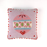 Pink Christmas pillow with an ornament design on a light pink background and red pom pom trim