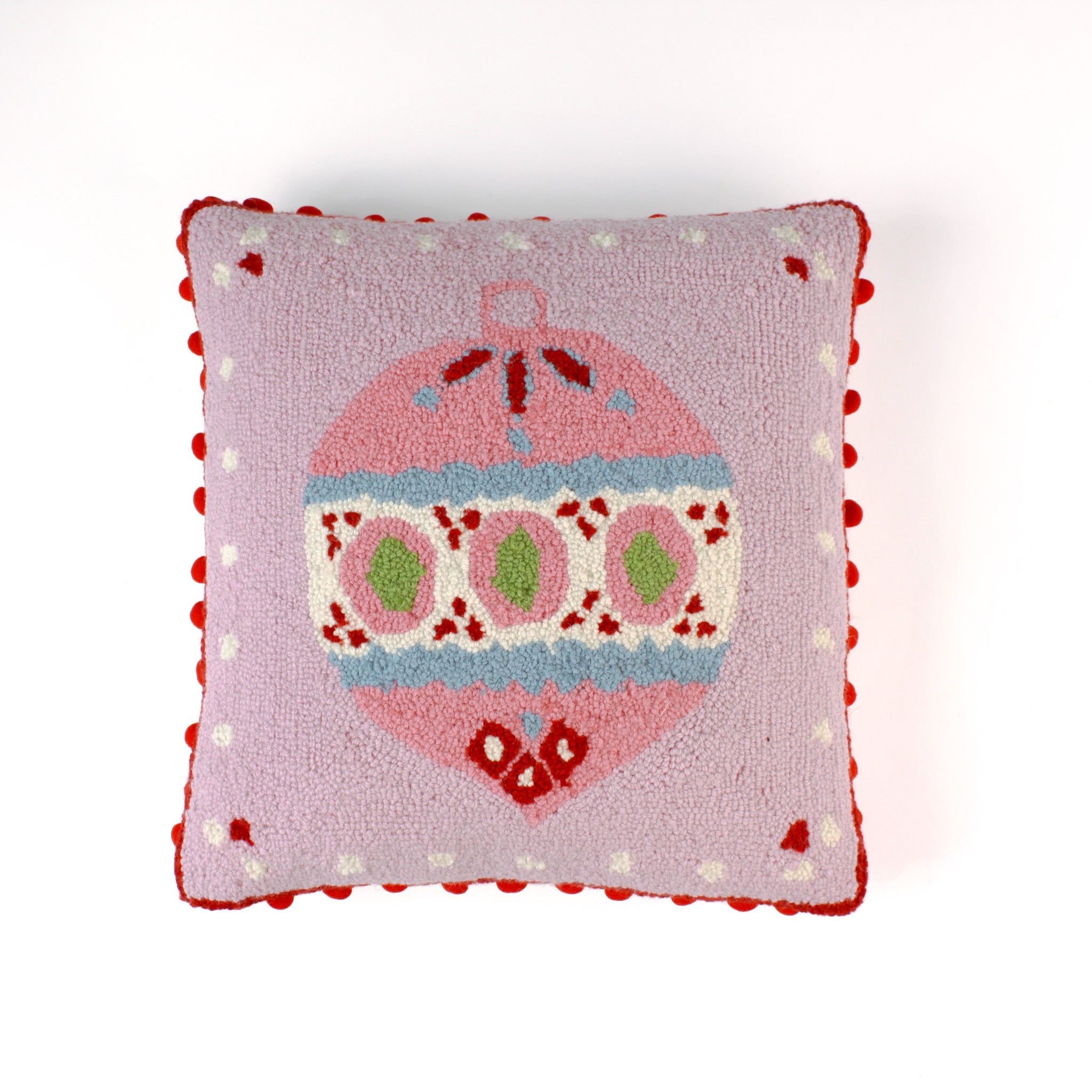 Pink Christmas pillow with an ornament design on a light pink background and red pom pom trim