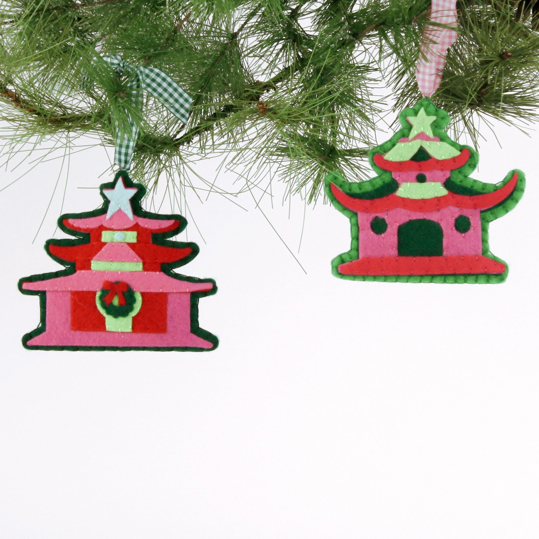 Two red and green pagoda-shaped Christmas ornaments hanging on a tree branch.