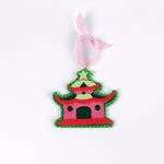 pink felt chinoiserie christmas ornaments in the shape of pagodas against a white background 