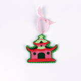 pink felt chinoiserie christmas ornaments in the shape of pagodas against a white background 