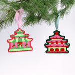 Two festive pagoda-shaped Christmas ornaments hanging on a tree branch.