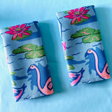 Folded pair of Sunken Gardens Flamingo cloth dinner napkins on blue background