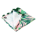 Palm leaf print napkin with green tropical foliage on a soft pink background and scalloped edge, stylish table linen perfect for Christmas tea towel styling, holiday entertaining, and seasonal home décor