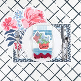 Patriotic table setting featuring a hydrangea and American flag place card, floral placemat, white dinner plate, and blue patterned napkin.