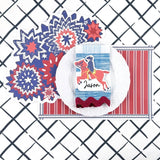 A styled patriotic table setting featuring a red white and blue starburst paper placemat, striped placemat, white plate, decorative napkin, and place card on a navy trellis patterned background.